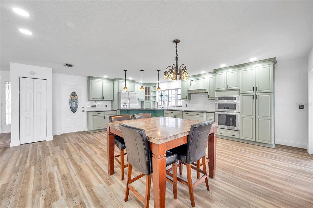 1520 Windmill Pointe Road Palm Harbor, FL 34685 - Photo 14 of 64 a kitchen with kitchen island stainless steel appliances a dining table chairs and wooden floor