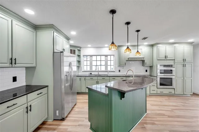 a kitchen with stainless steel appliances granite countertop a sink a refrigerator and a refrigerator