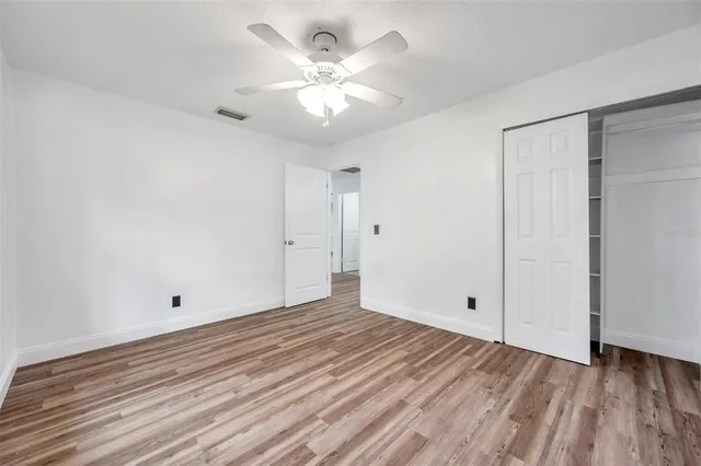 a view of empty room with wooden floor and ceiling fan