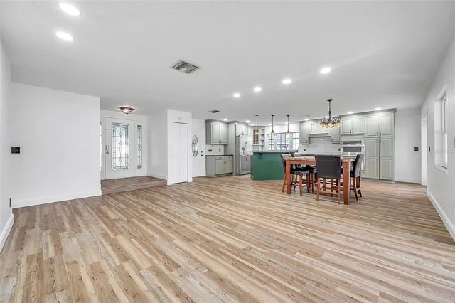 a kitchen with stainless steel appliances granite countertop a kitchen island hardwood floor sink stove dining table and chairs