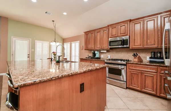 a kitchen with stainless steel appliances granite countertop a sink a stove and cabinets