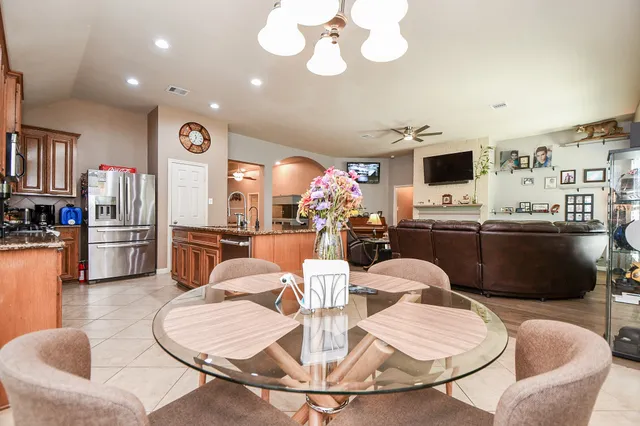 a kitchen with stainless steel appliances kitchen island granite countertop a refrigerator a stove a microwave oven a dining table and chairs with wooden floor