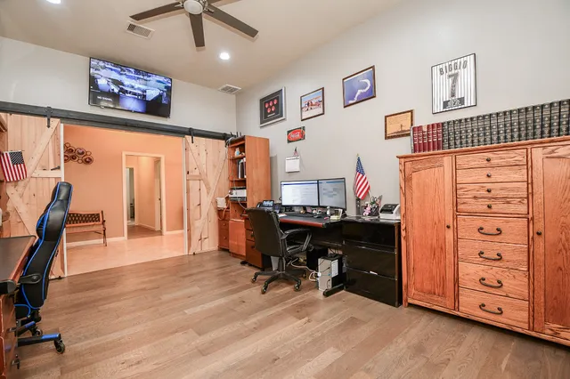 a view of a workspace with furniture and a ceiling fan