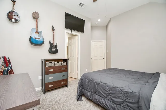 a bedroom with a bed and a flat tv screen on dresser
