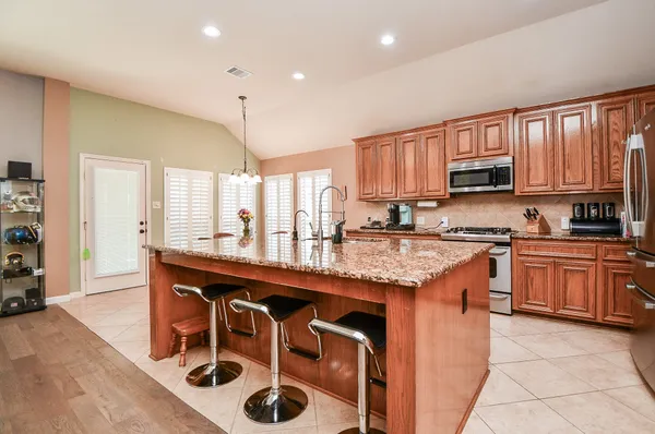 a kitchen with stainless steel appliances granite countertop a stove a sink and a refrigerator