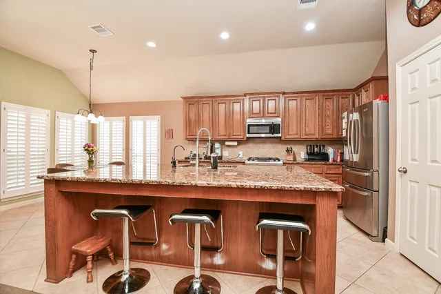 a kitchen with kitchen island granite countertop wooden cabinets and a refrigerator