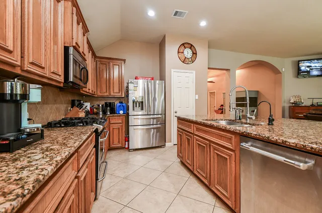a kitchen with stainless steel appliances granite countertop a stove a sink and a refrigerator