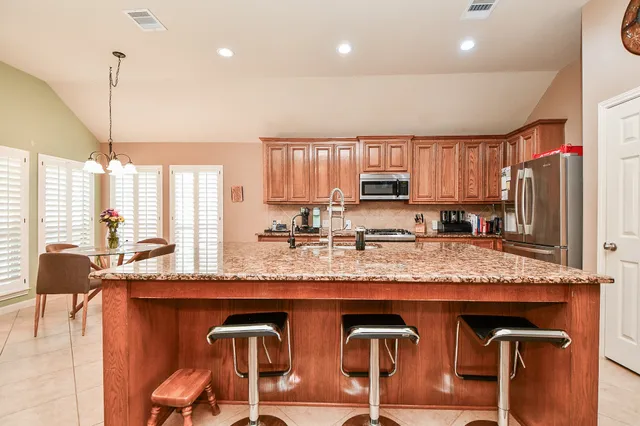 a kitchen with stainless steel appliances granite countertop wooden cabinets a stove a sink and a large window