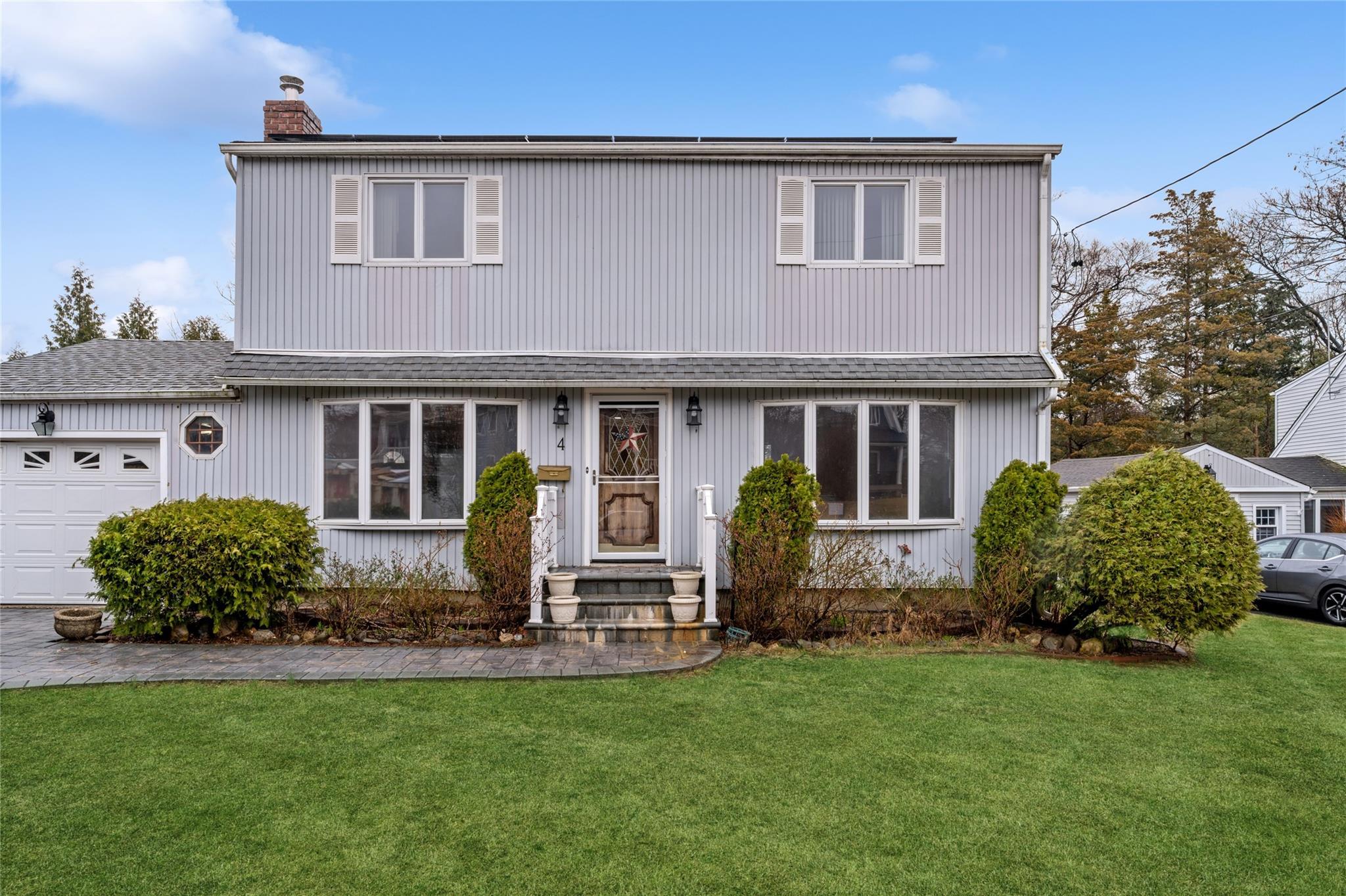 Traditional home featuring a front lawn, a chimney, a garage, and roof with shingles