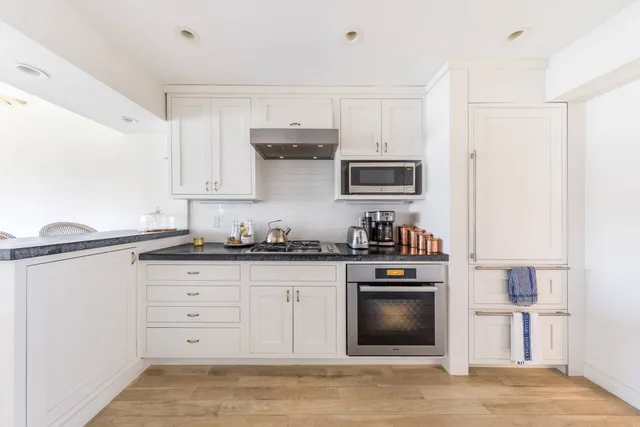 a kitchen with granite countertop a stove top oven microwave and refrigerator