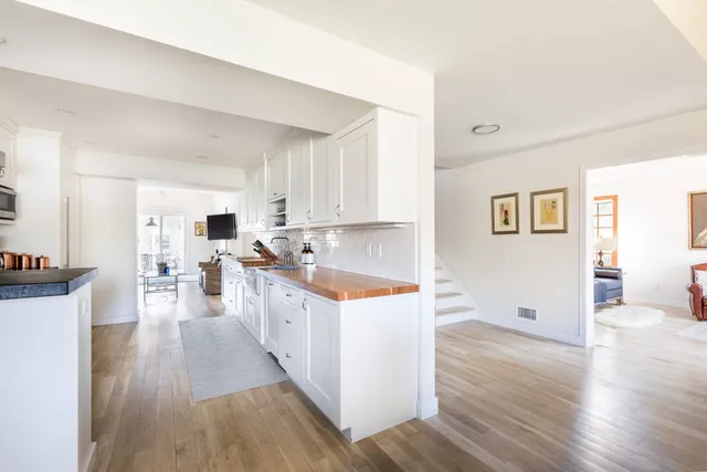a kitchen with white cabinets and wooden floor