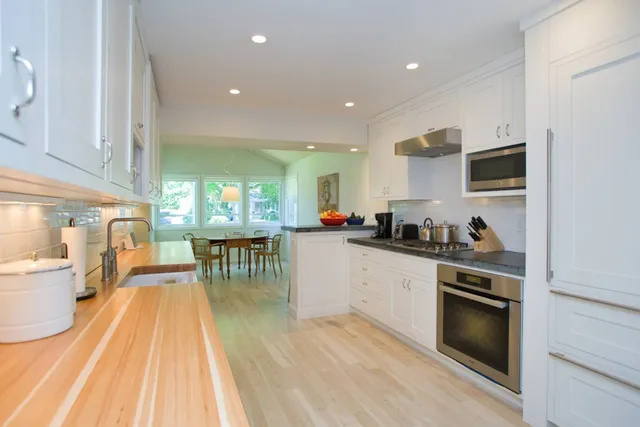 a kitchen with stainless steel appliances granite countertop a stove a sink a dining table and chairs