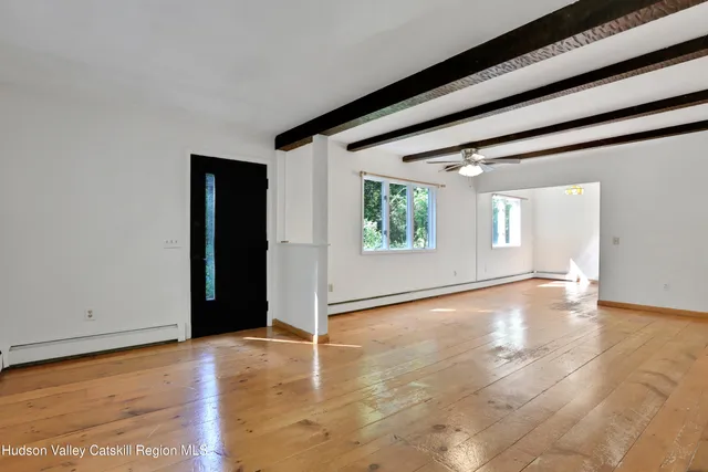 a view of an empty room with window and wooden floor