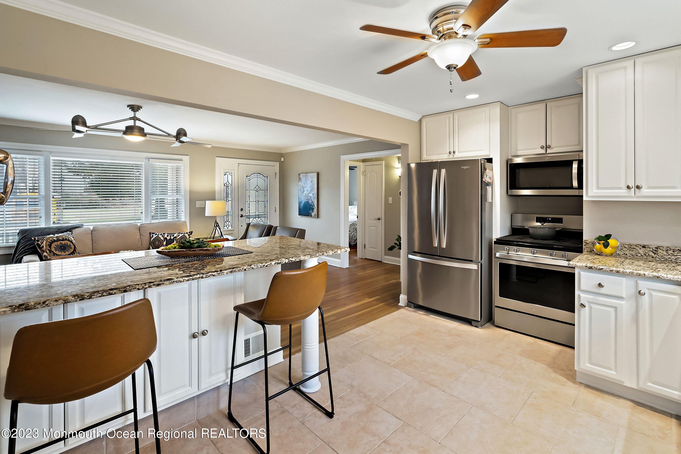 554 Hopping Road Belford, NJ 07718 - Photo 12 of 26 a kitchen with stainless steel appliances a refrigerator a stove a sink and chairs