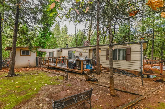 a backyard of a house with wooden fence and large trees