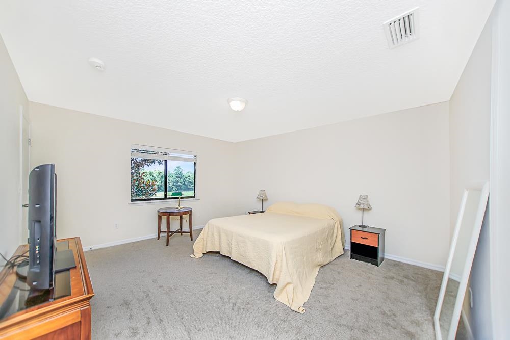 499 Cabernet Place St. Augustine, FL 32084 - Photo 10 of 30 a spacious bedroom with a bed and a flat screen tv