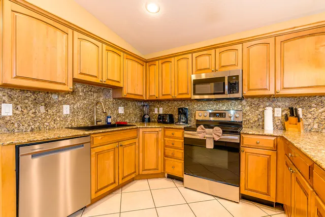 a kitchen with stainless steel appliances granite countertop a sink a stove a microwave a dining table and chairs