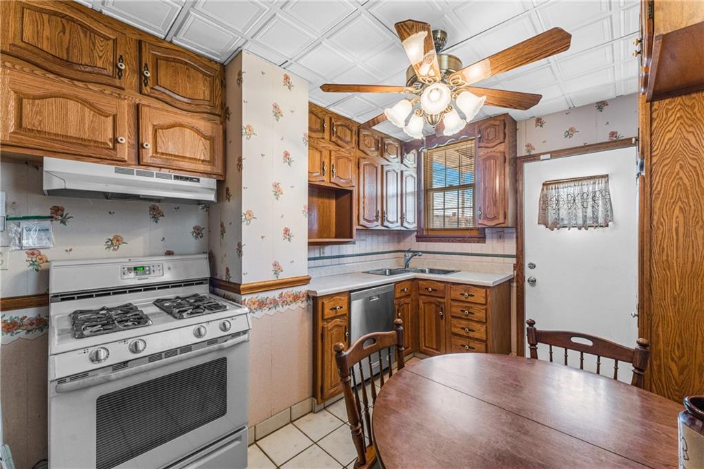 111 Sarah Street McKees Rocks, PA 15136 - Photo 4 of 30 a kitchen with stainless steel appliances granite countertop a stove a sink dishwasher and a dining table with wooden cabinet