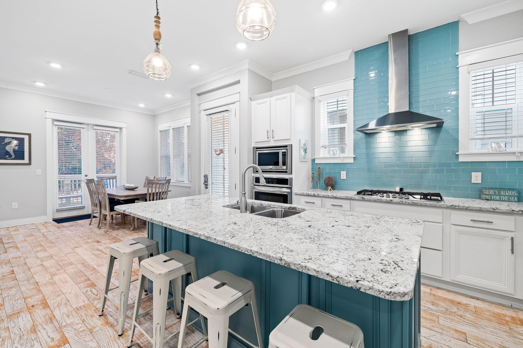 a kitchen with stainless steel appliances granite countertop a stove top oven a sink dishwasher and chairs with wooden floor