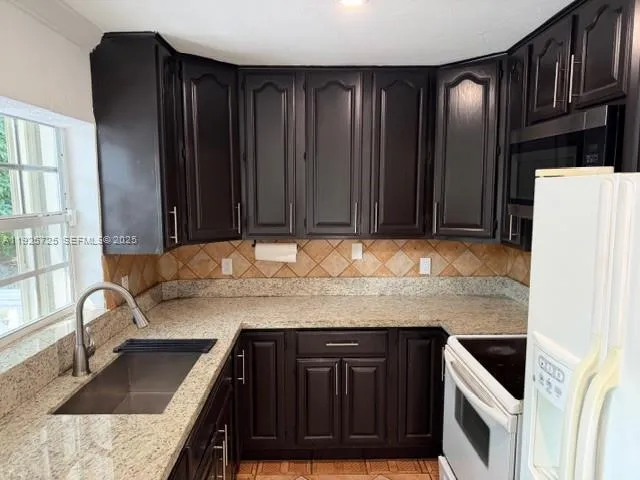 a kitchen with granite countertop a sink a stove and a refrigerator