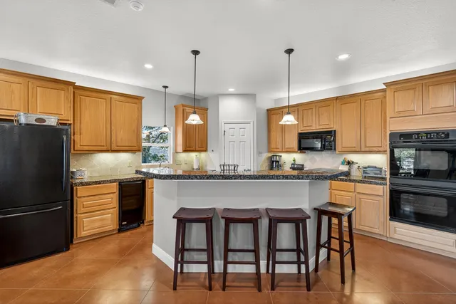 a kitchen with stainless steel appliances granite countertop a stove a sink a refrigerator a microwave oven with a dining table and chairs