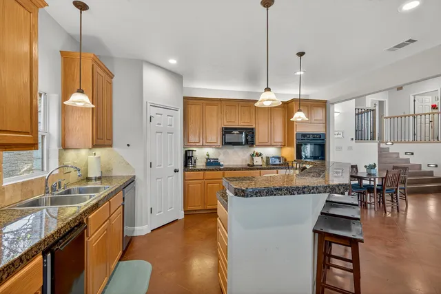 a large kitchen with kitchen island granite countertop a large center island a sink a stove and a wooden floors
