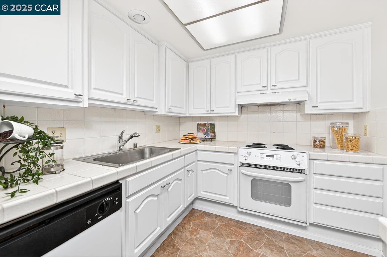 1400 Ptarmigan Drive, Unit 2 Walnut Creek, CA 94595 - Photo 12 of 44 a kitchen with granite countertop white cabinets and white appliances