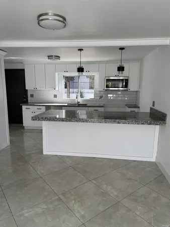 a large kitchen with granite countertop a stove a sink and a granite counter tops