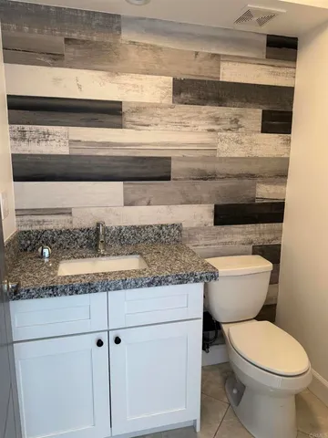a bathroom with a granite countertop toilet and a sink