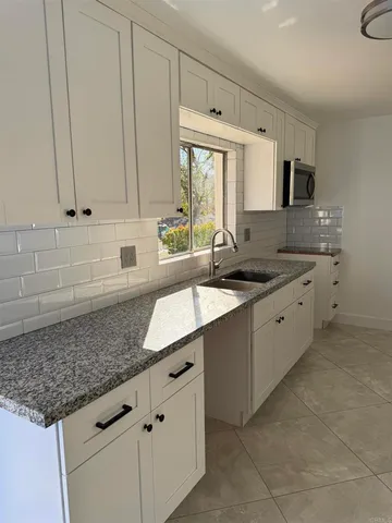 a kitchen with granite countertop a sink a stove and cabinets