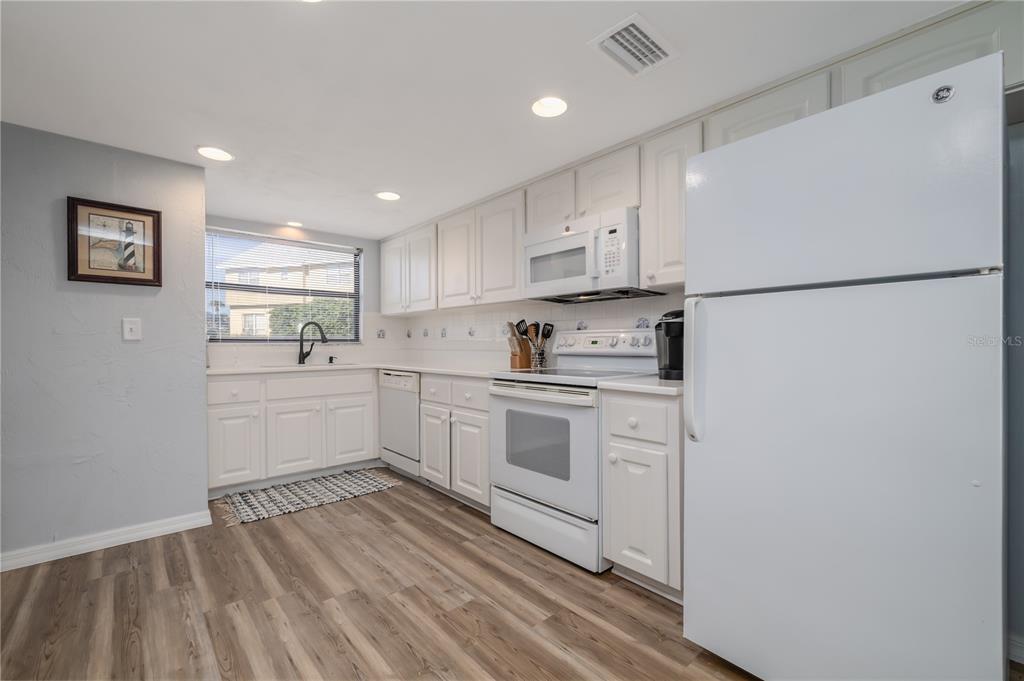 4786 South Atlantic Avenue, Unit 4B Ponce Inlet, FL 32127 - Photo 11 of 22 a kitchen with white cabinets and white appliances