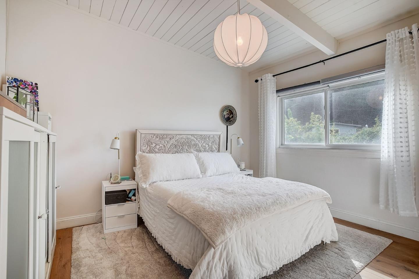 274 Hillside Drive Pacifica, CA 94044 - Photo 18 of 56 a bedroom with a large bed and a chandelier