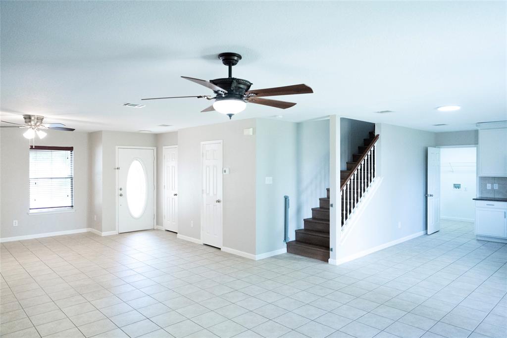 8805 Graywolf Ridge Trail Fort Worth, TX 76244 - Photo 20 of 23 Expansive open-concept living area featuring tile flooring, a white front entry door with an oval glass insert, and two ceiling fans with integrated lighting