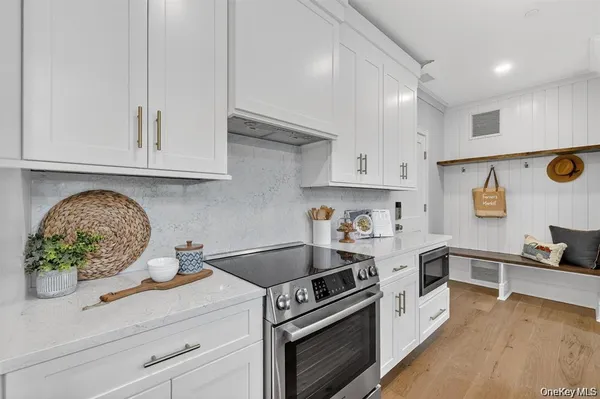 a kitchen with stainless steel appliances granite countertop a stove a sink and a white wooden cabinets