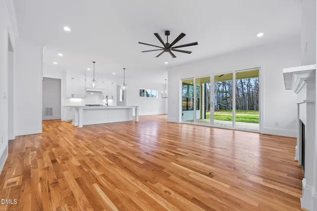 a large kitchen with stainless steel appliances kitchen island granite countertop a stove a sink a refrigerator and a wooden floor