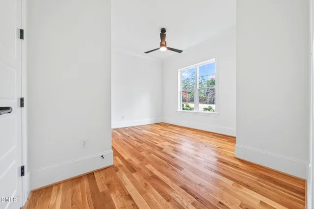 a view of an empty room with wooden floor and a window