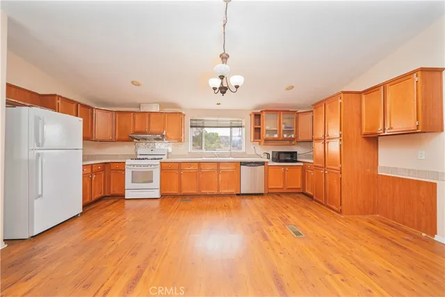 a kitchen with stainless steel appliances granite countertop a refrigerator a oven a sink dishwasher and white cabinets with wooden floor