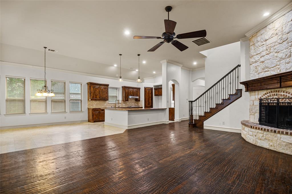 961 Deer Run Prosper, TX 75078 - Photo 16 of 34 a view of an empty room with wooden floor and a kitchen