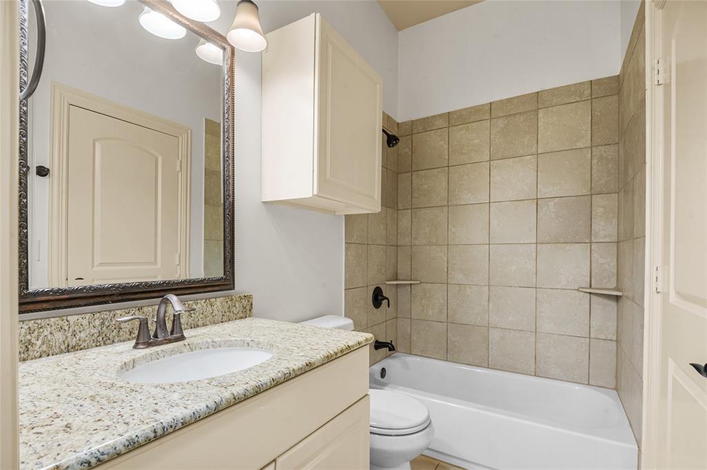 961 Deer Run Prosper, TX 75078 - Photo 24 of 34 a bathroom with a granite countertop sink a toilet and bathtub