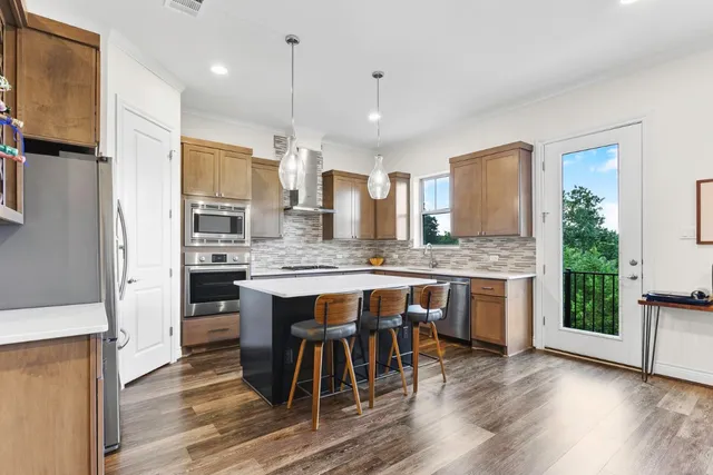 a kitchen with granite countertop stainless steel appliances a sink stove and refrigerator
