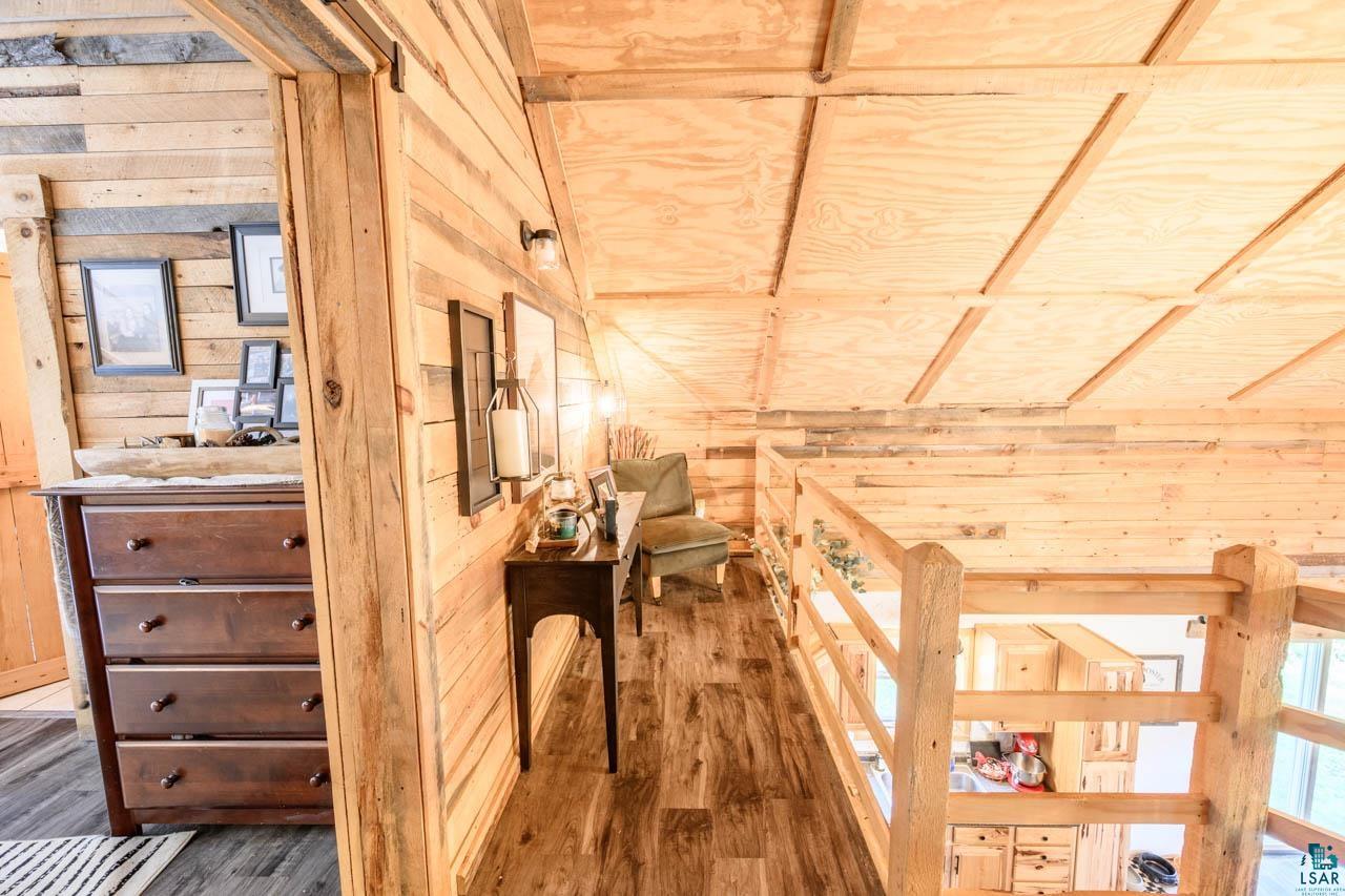 7603 Levander Road Embarrass, MN 55732 - Photo 21 of 51 Charming wood-paneled interior showcasing exposed beam ceiling construction, wood-finish flooring throughout, and abundant natural light from multiple windows