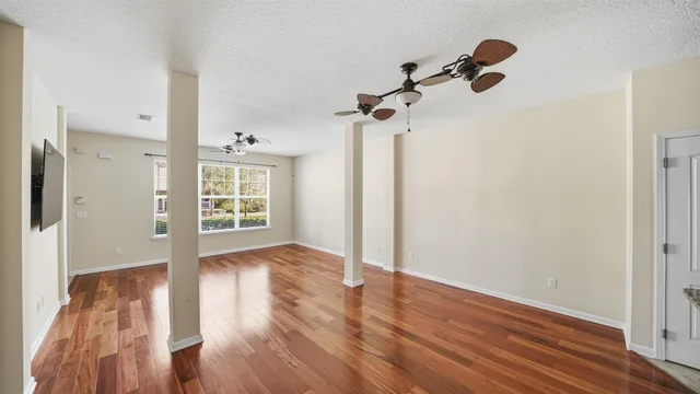 a view of an empty room with wooden floor and a window