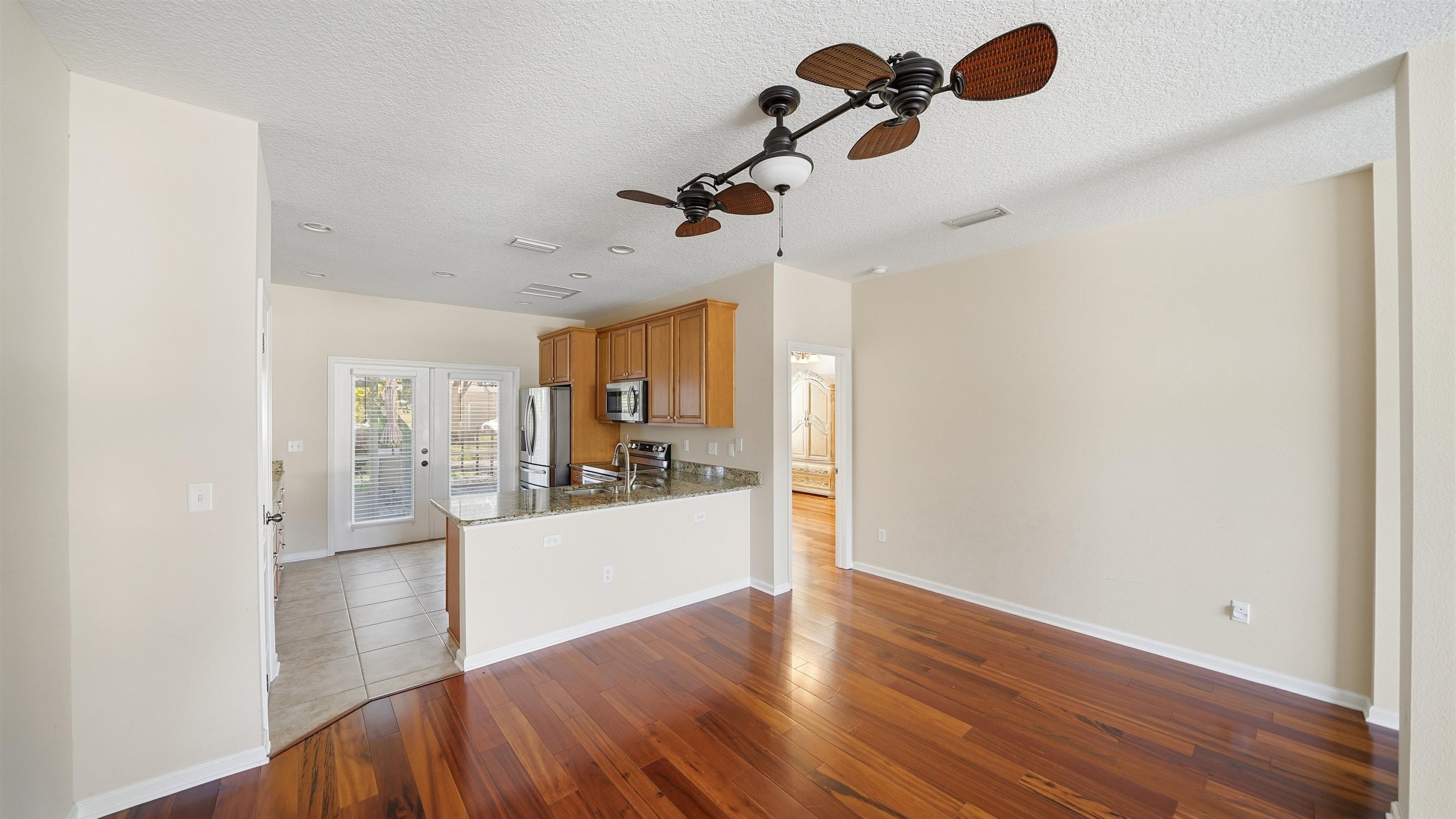 1121 Overdale Road St. Augustine, FL 32080 - Photo 9 of 65 Kitchen featuring dark stone countertops, light wood-style flooring, a ceiling fan, stainless steel appliances, and a peninsula