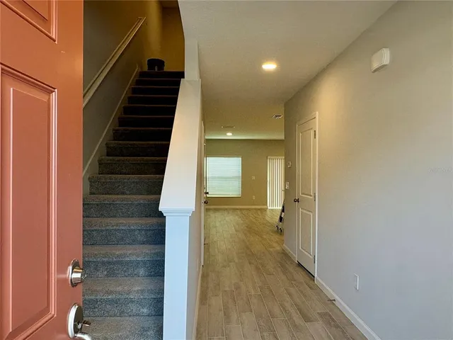 a view of a hallway with wooden floor and staircase