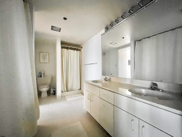 a spacious bathroom with a granite countertop sink a toilet and a shower