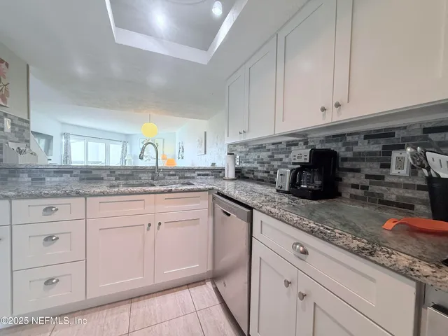 a kitchen with granite countertop white cabinets and white appliances