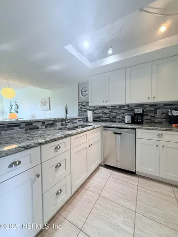 a kitchen with granite countertop white cabinets white stainless steel appliances with a sink and dishwasher
