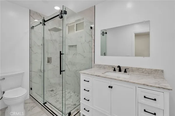 a bathroom with a shower sink vanity mirror and toilet