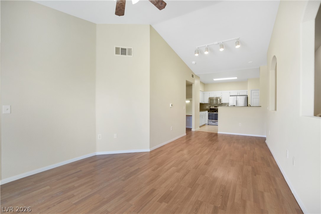 10550 West Alexander Road, Unit 2171 Las Vegas, NV 89129 - Photo 4 of 17 Smooth wood floors flow seamlessly through this open layout toward a well-equipped kitchen.