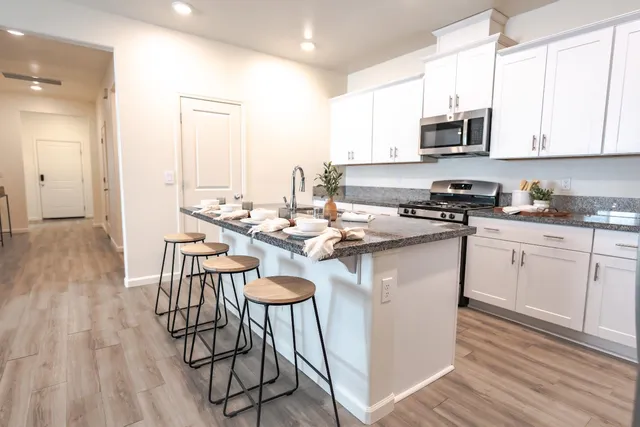 a kitchen with stainless steel appliances a white table chairs and a wooden floors